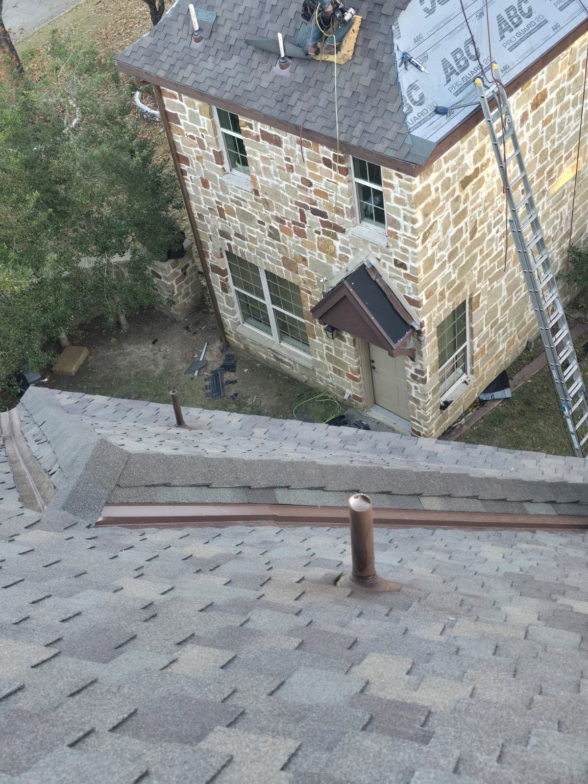 Roof replacement in progress on a two-story stone home