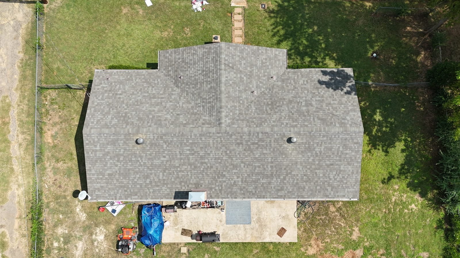 Aerial view of severe storm damage with tarped roof and scattered debris in Shreveport-Bossier City